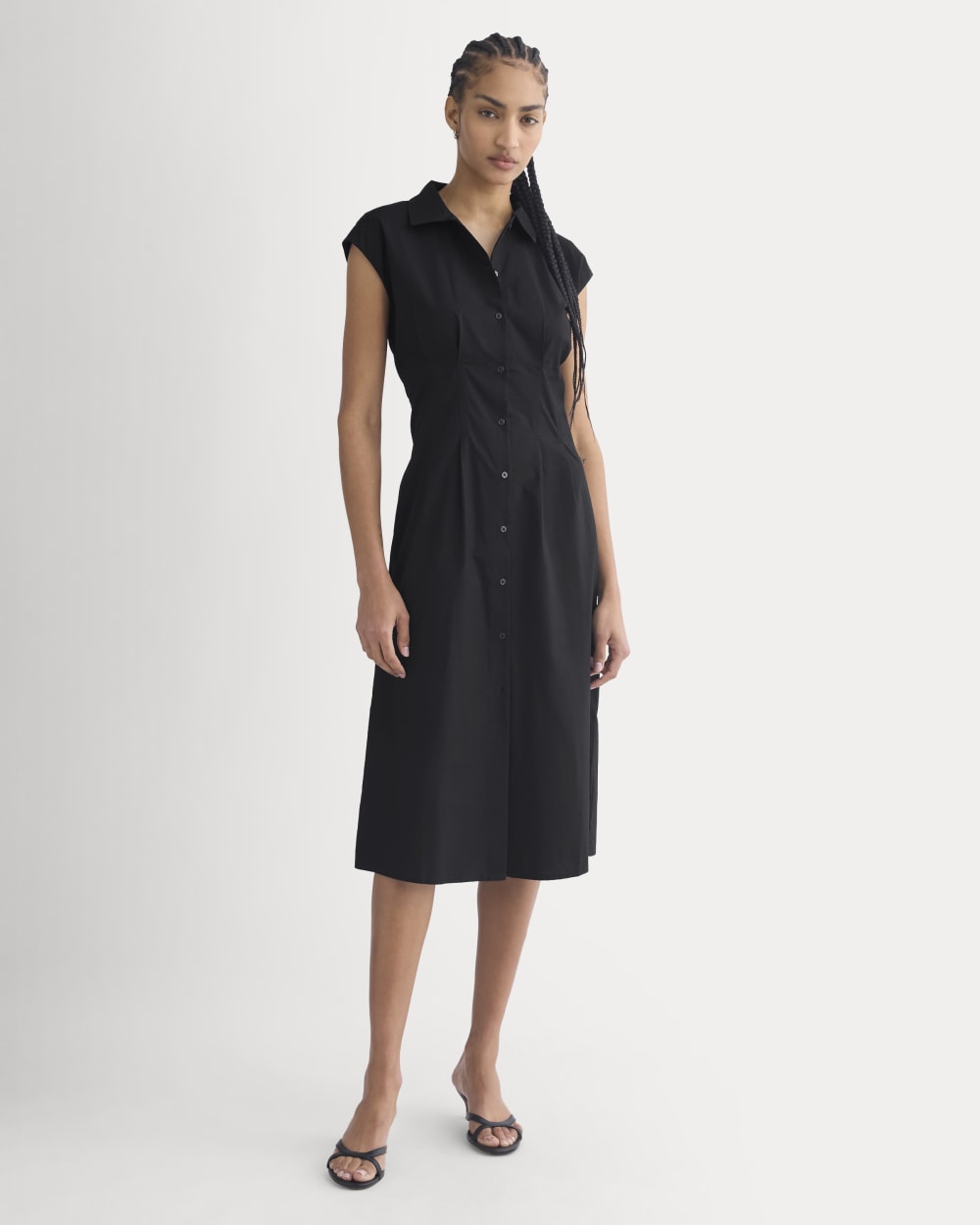 Black sleeveless cotton shirt dress with a button front, waist pleats and a midi skirt